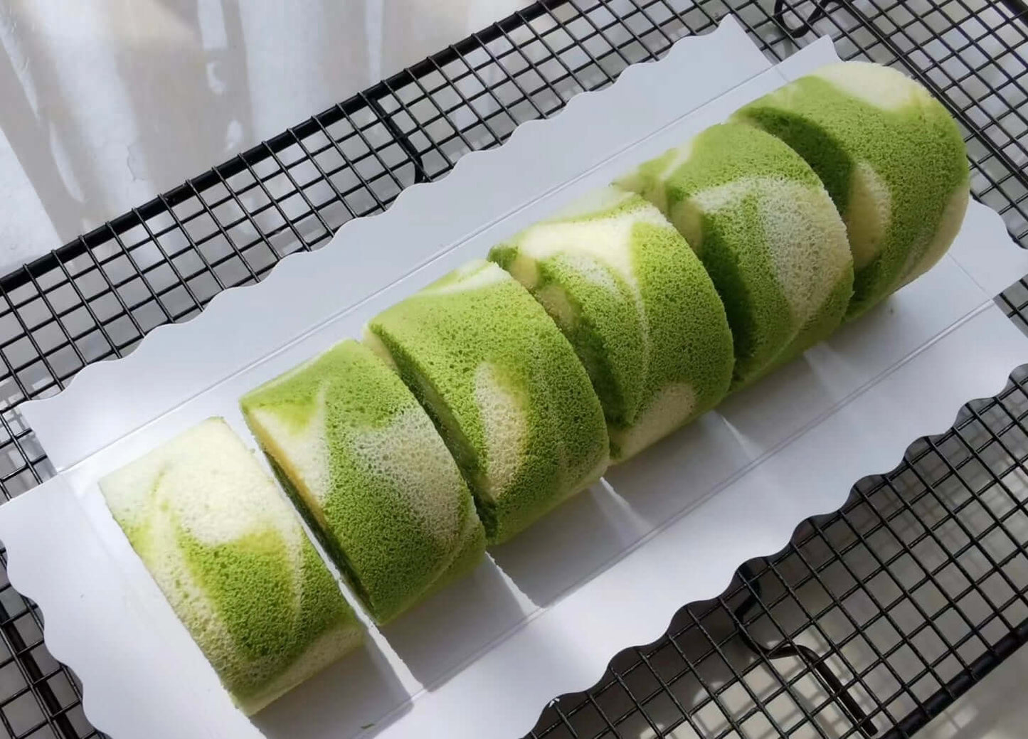 Slices of low sugar pandan coconut cake roll showcasing the light green sponge and creamy filling.