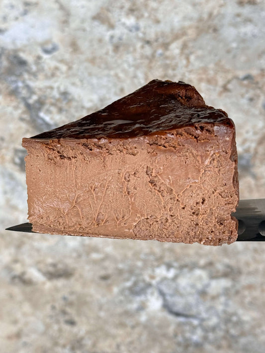 gluten free Chocolate burnt basque cheesecake slice with caramelized top on a serving spatula
