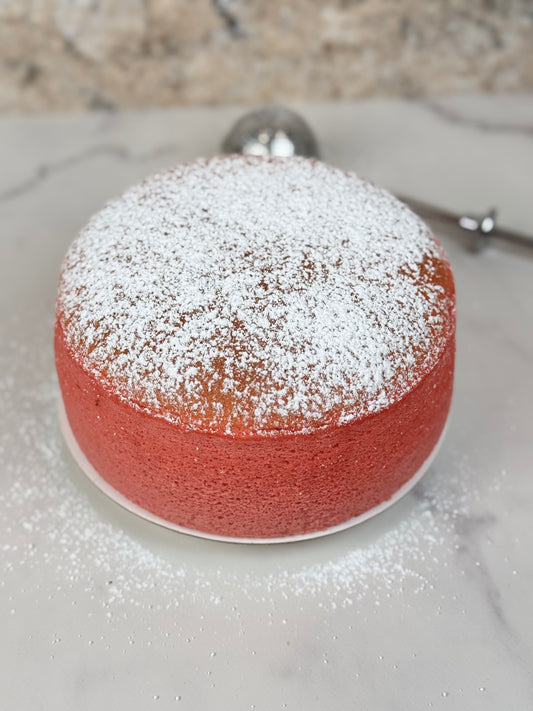 Strawberry Japanese souffle cheesecake dusted with powdered sugar on a marble surface.