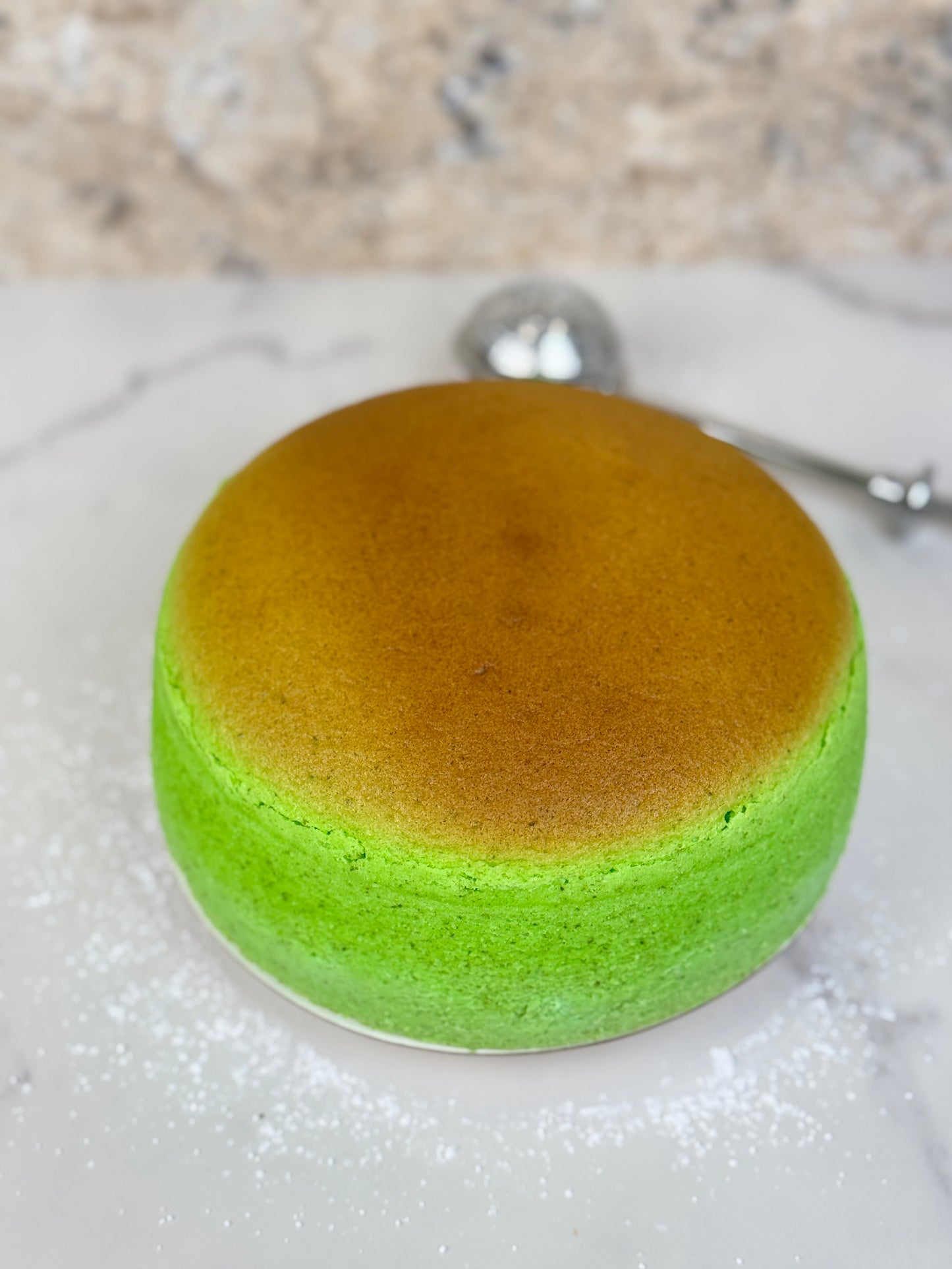 Pandan Japanese souffle cheesecake 6 inch organic with a soft green and brown top on a marble surface
