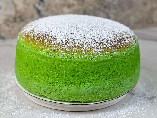 Pandan Japanese souffle cheesecake topped with powdered sugar, showcasing its vibrant green color and fluffy texture.
