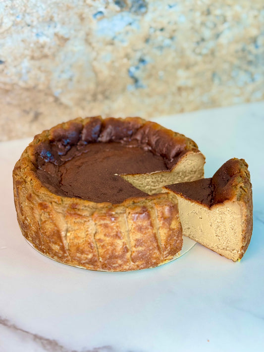 Vietnamese coffee burnt cheesecake gluten-free with a slice cut out, showcasing its creamy texture and caramelized top.