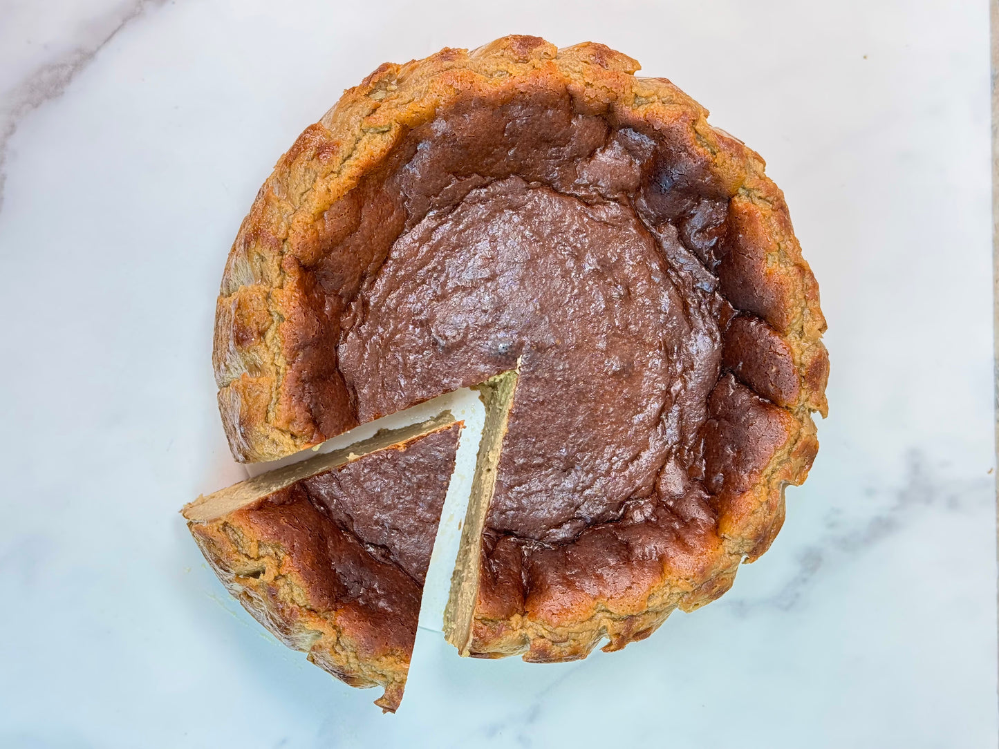 Vietnamese coffee burnt cheesecake gluten-free with a slice taken out, showcasing its creamy texture and burnt caramelized top.