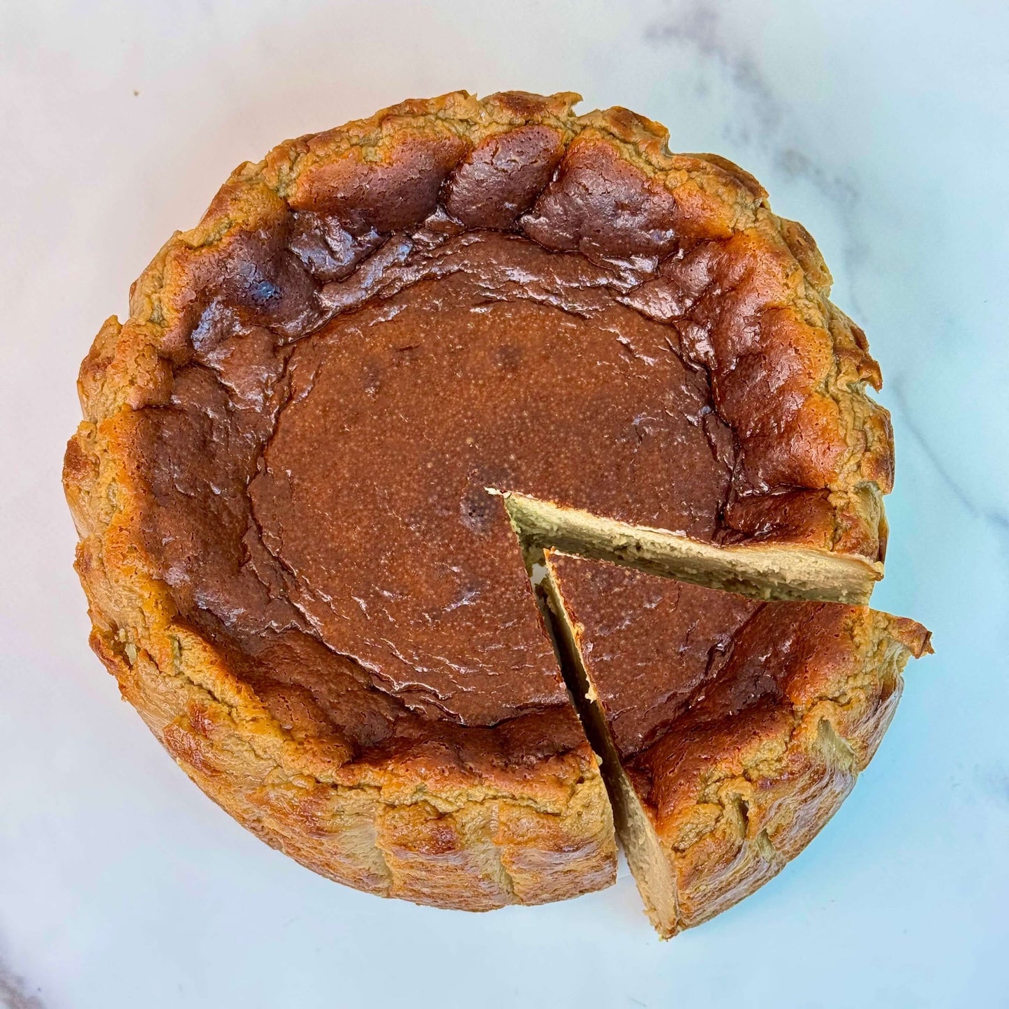 Vietnamese coffee burnt cheesecake gluten-free with a slice cut out, showcasing its smooth, velvety texture.