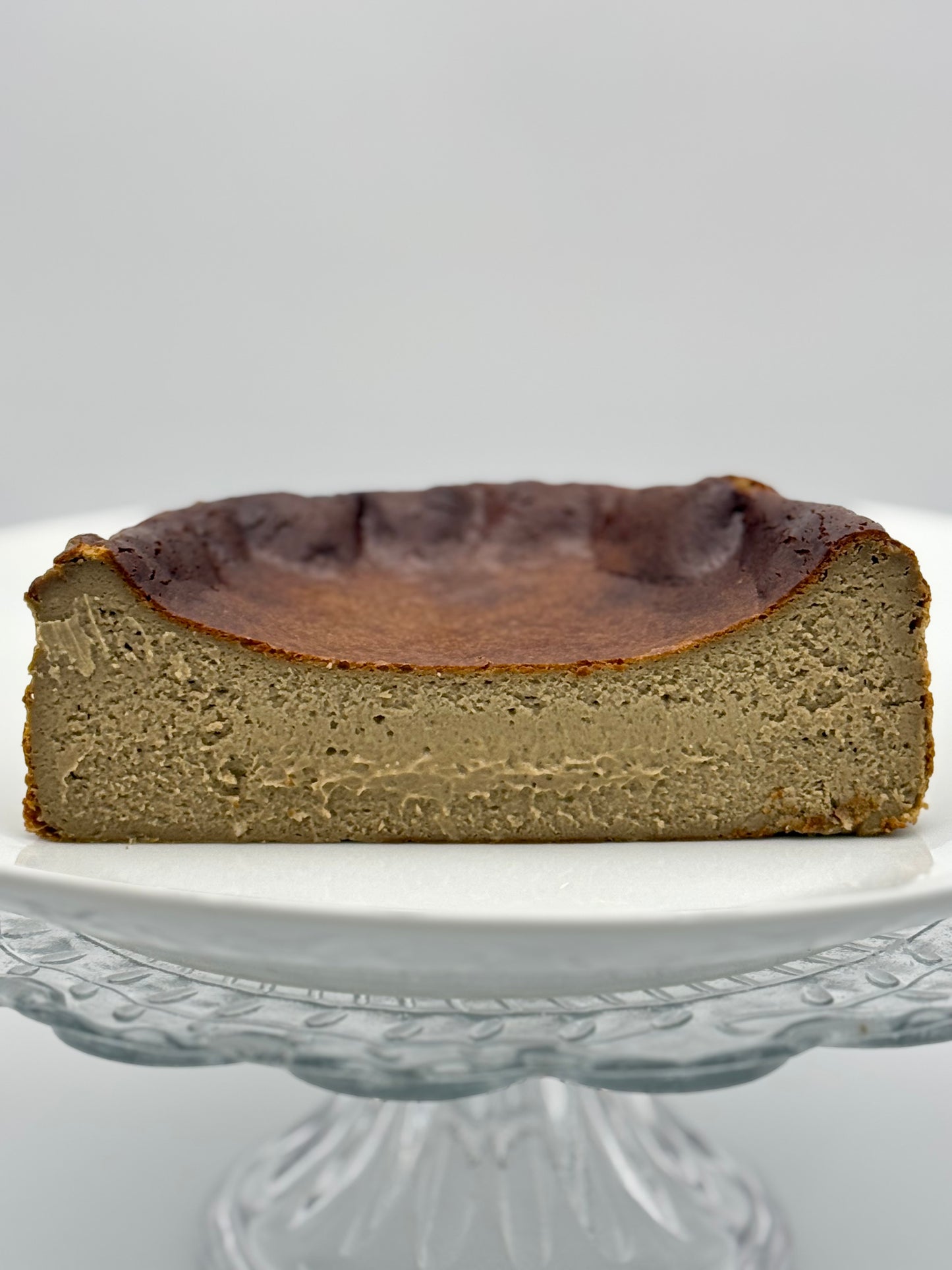 Creamy burnt Basque cheesecake infused with roasted hojicha tea, boasting a caramelized crust and a smooth, earthy-flavored center.