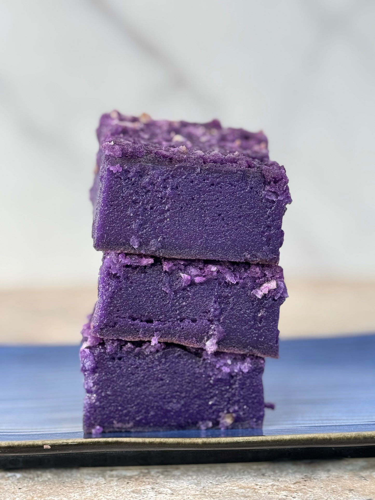 Stack of vibrant purple Ube Coconut Butter Mochi Cake Bars, showcasing their chewy texture and rich color.