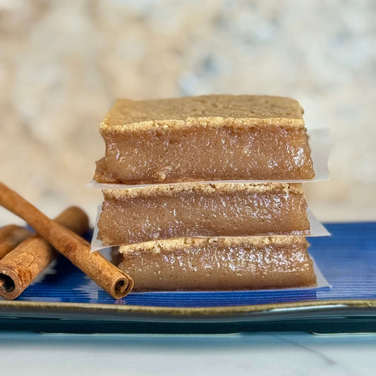 Vegan Cinnamon Maple Butter Mochi stacked pieces with cinnamon sticks on a blue plate.