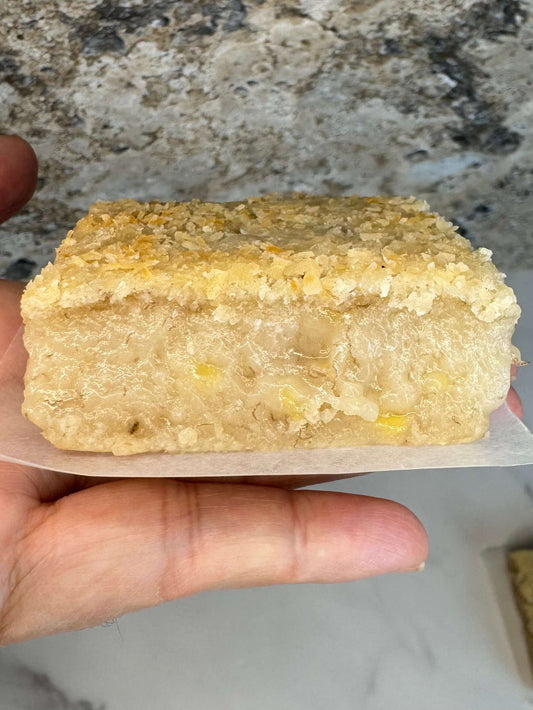 Vegan Banana Mochi Cake Bar Organic Sugar Free holding in hand, showcasing its soft texture and golden topping.