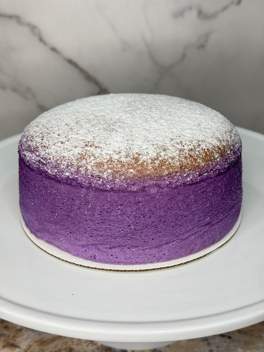 Ube Souffle Japanese Cheesecake with a light dusting of powdered sugar on top, displayed on a white plate.