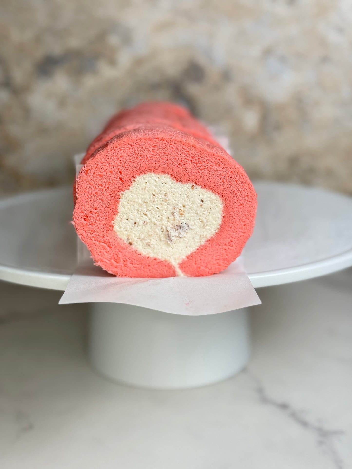 Rose Strawberry Cake Roll Organic showcasing a fluffy pink sponge and creamy filling on a white display plate.