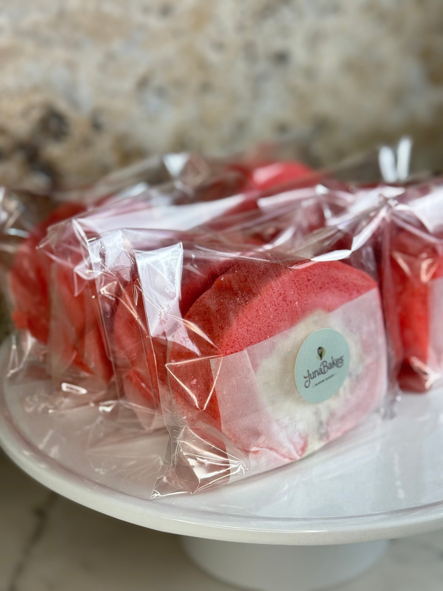 Rose Strawberry Cake Roll Organic wrapped in clear plastic on a white serving plate.