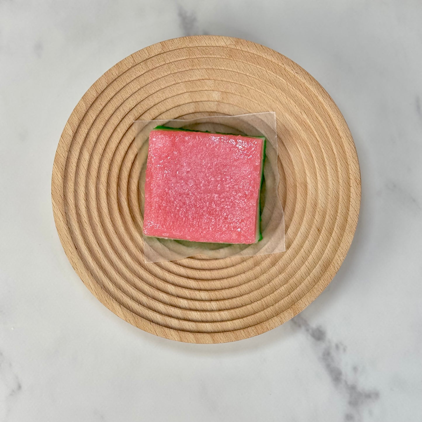 Vegan tri-color chi chi dango mochi bars on a wooden plate, showcasing vibrant pastel layers.