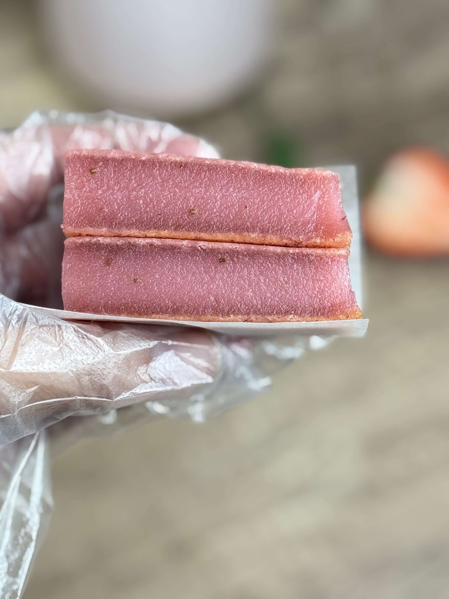 Vegan strawberry mochi cake bars held in a hand, showcasing their chewy and soft texture.