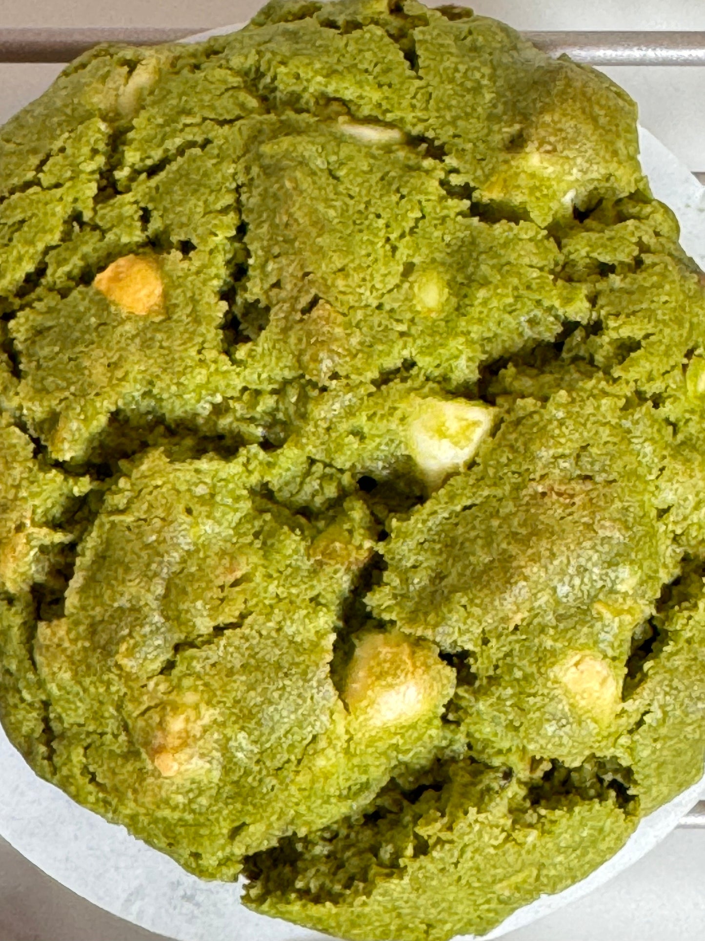 Matcha White Chocolate Pistachio Cookie showcasing a vibrant green color with chunks of white chocolate and pistachios.