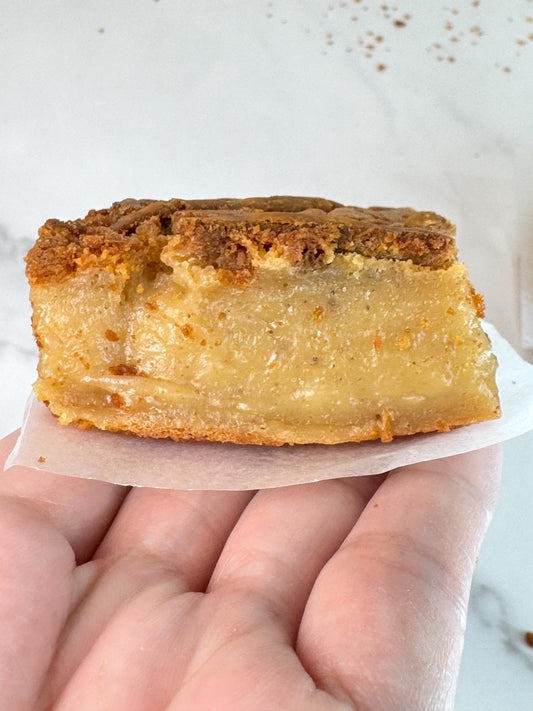 Vegan gluten free peanut butter mochi piece held in hand showing rich texture and golden crust.