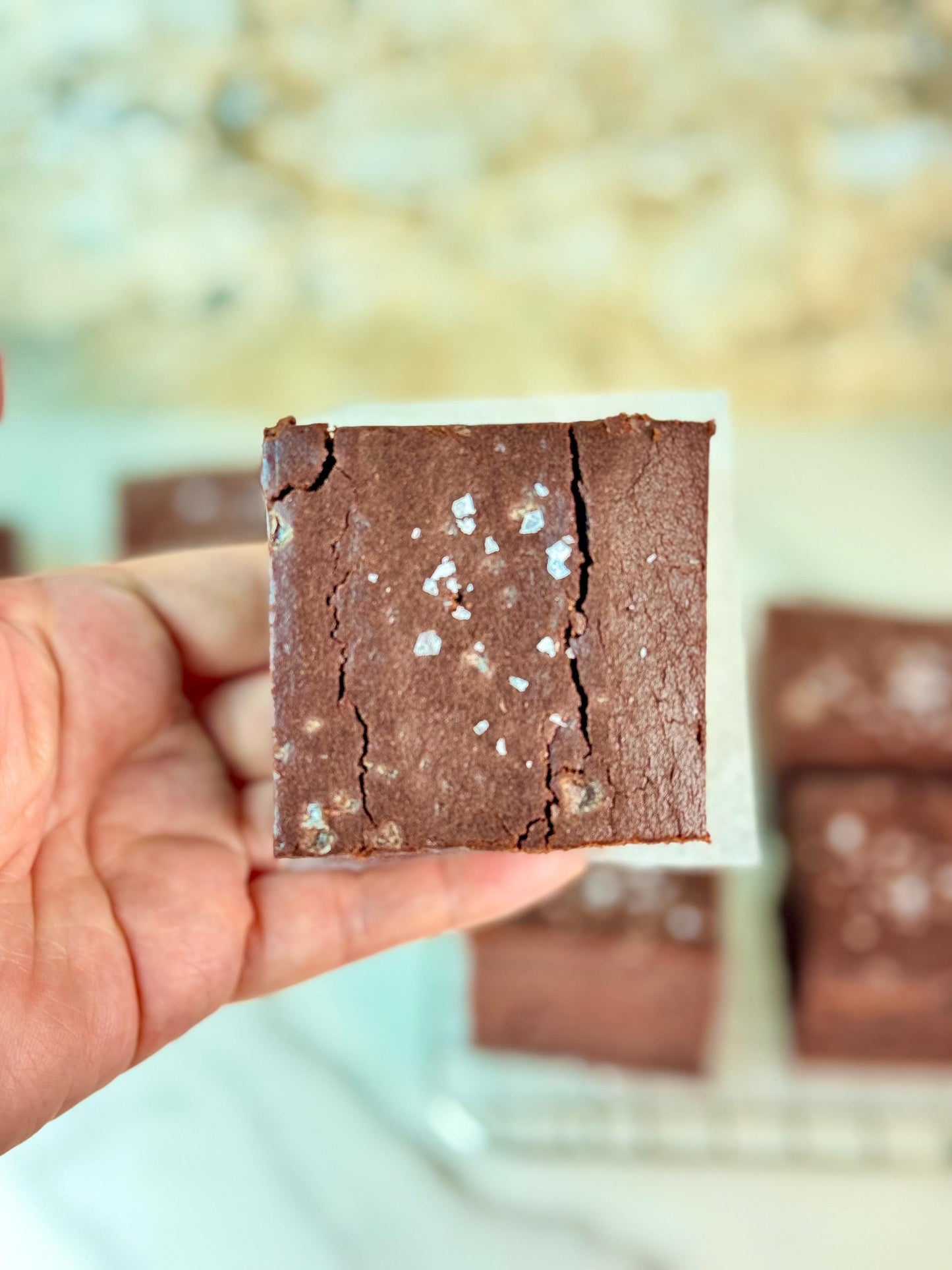 Delicious gluten free vegan mochi brownie with flaky sea salt, held in hand.