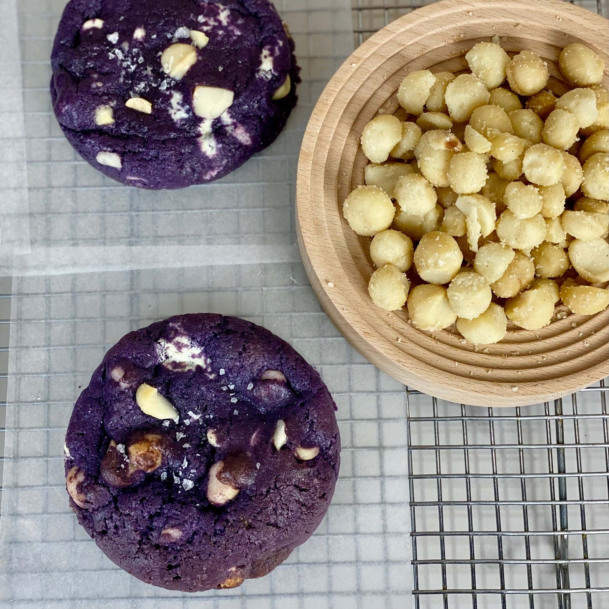 Ube White Chocolate Macadamia Cookies with macadamia nuts on a wooden plate, showcasing their rich color and texture.