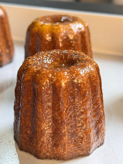 Traditional French cannelés with a caramelized crust and tender vanilla-rum custard center, baked to golden perfection in copper molds.