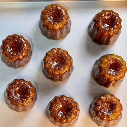 Traditional French cannelés with a caramelized crust and tender vanilla-rum custard center, baked to golden perfection in copper molds.