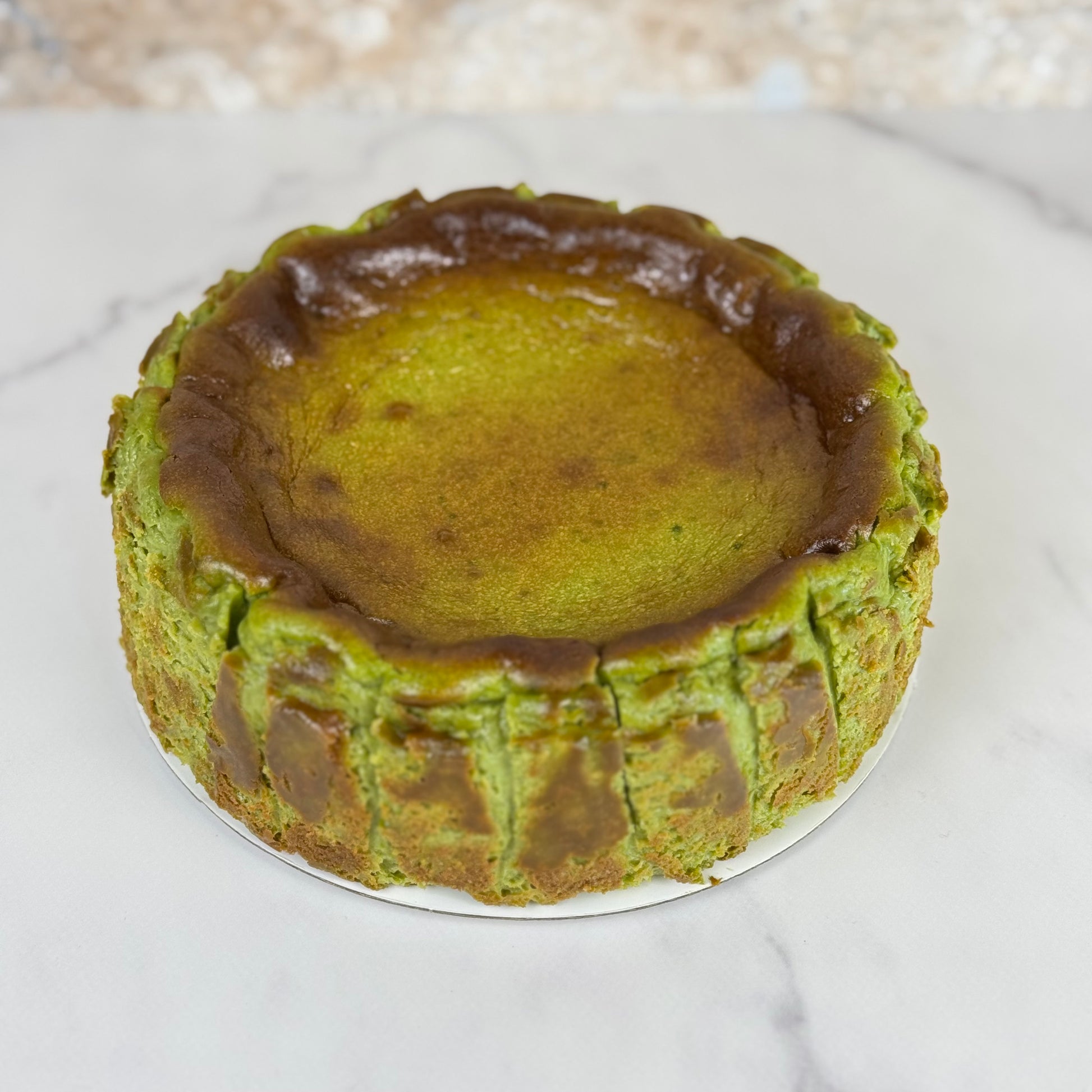gluten-free matcha Burnt Basque cheesecake 6 Inch on a marble surface, showcasing its caramelized top.