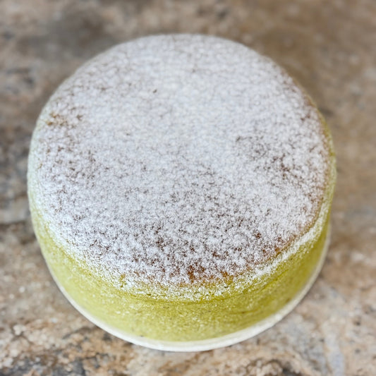 Pistachio Japanese souffle cheesecake Organic 6 Inch topped with powdered sugar on a marble surface.