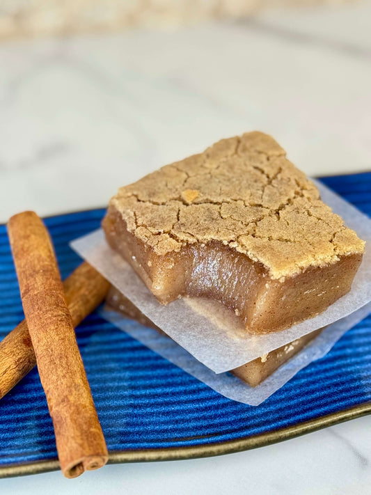 Vegan Cinnamon Maple Butter Mochi presented on a blue plate with cinnamon sticks, showcasing its soft and chewy texture.