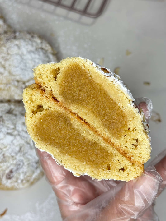 Almond Croissant Cookie With Frangipane filling, revealing soft, tender center in a person's hand.