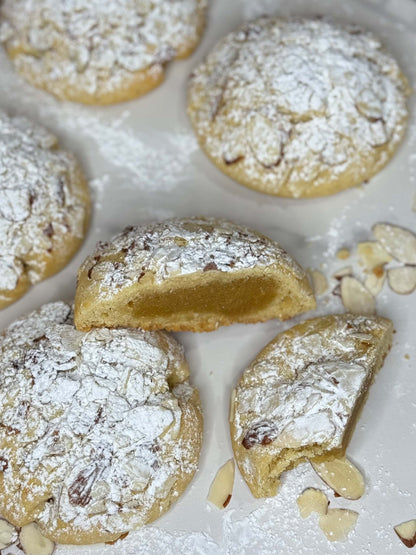 Almond croissant cookie with frangipane filling on a white plate, dusted with powdered sugar.