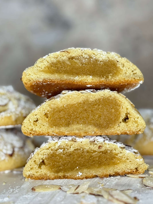 Almond croissant cookie with frangipane filling, showcasing a soft, tender center and golden edges layered in powdered sugar.