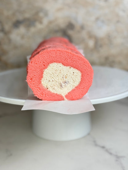 Rose Strawberry Cake Roll Organic showcasing a fluffy pink sponge and creamy filling on a white display plate.