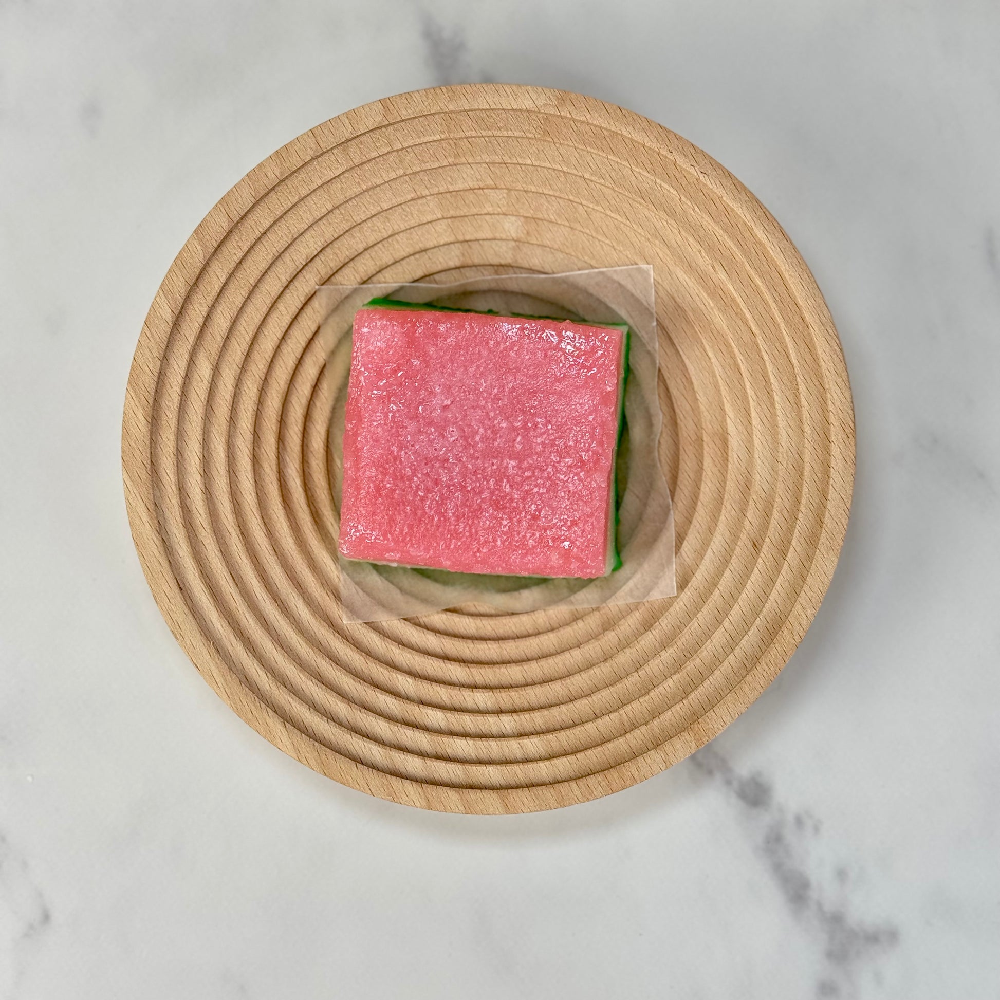 Vegan tri-color chi chi dango mochi bars on a wooden plate, showcasing vibrant pastel layers.