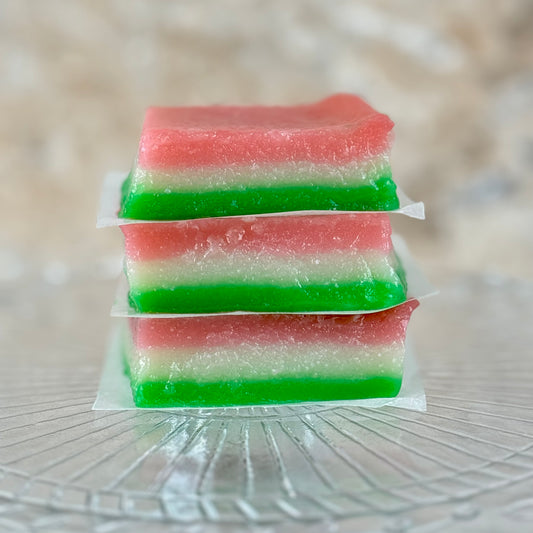 Vegan tri-color chi chi dango mochi bars stacked on a glass plate, featuring pink, white, and green layers.