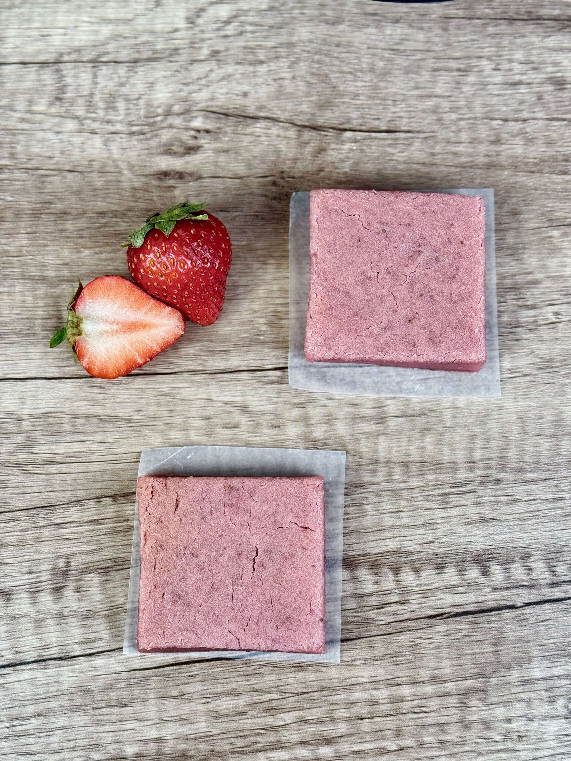 Vegan Strawberry Mochi Cake Bars displayed with fresh strawberries on a wooden surface, highlighting their chewy texture.