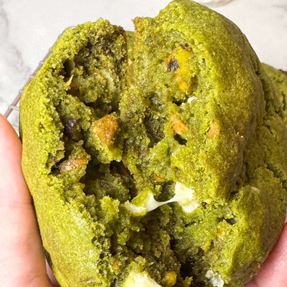 Soft matcha cookie with roasted pistachios and white chocolate chunks, vibrant green color and nutty, sweet flavor blend.